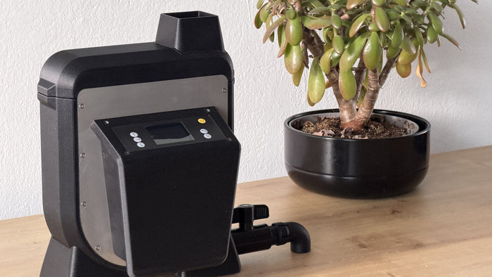The Fränk film processor prototype on a wooden desk next to a potted jade plant