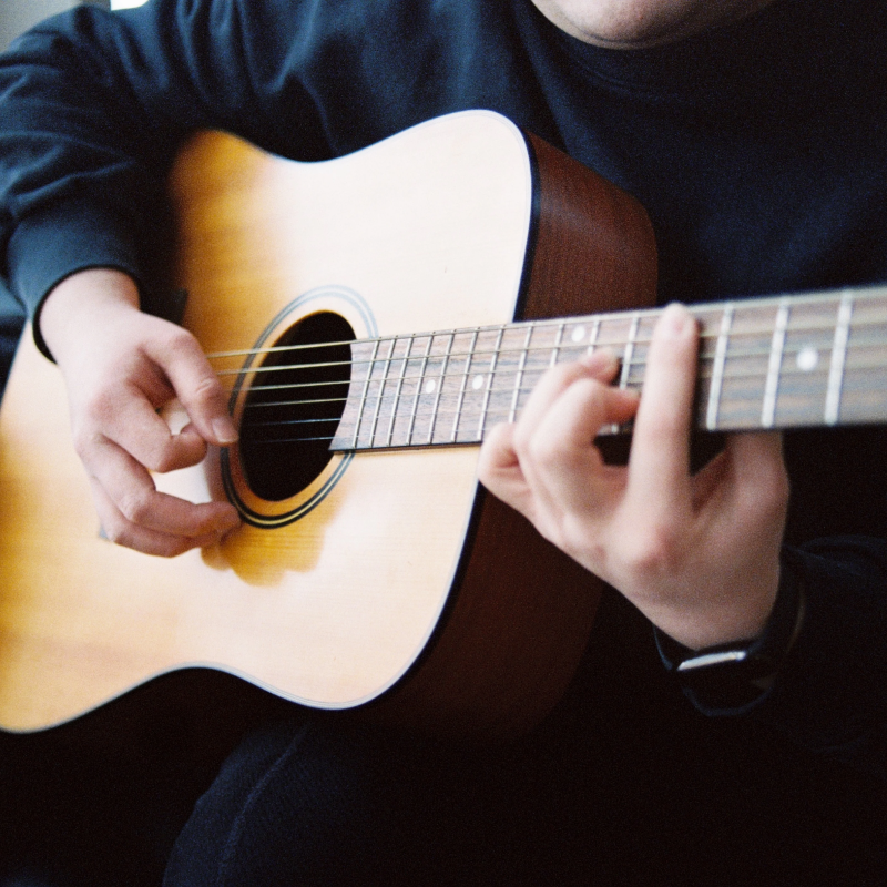 REFLX LAB 640T sample photo: close-up of hands playing an acoustic guitar indoors under tungsten light