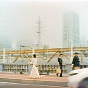 Fortuna C200 110 sample photo: pedestrians crossing a bridge in hazy city light with a hotel tower in the background