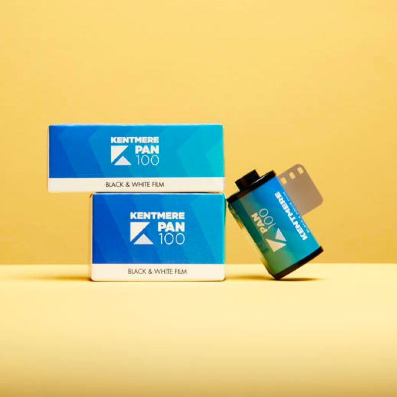 Two Kentmere PAN 100 film boxes with 35mm canister on yellow background showing black and white film packaging
