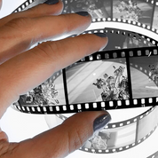 Hand holding developed B&W reversal slide film strip processed with ADOX Scala kit showing positive transparency frames