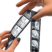 Hands holding two developed B&W reversal slide film strips examining positive transparency frames from ADOX Scala processing