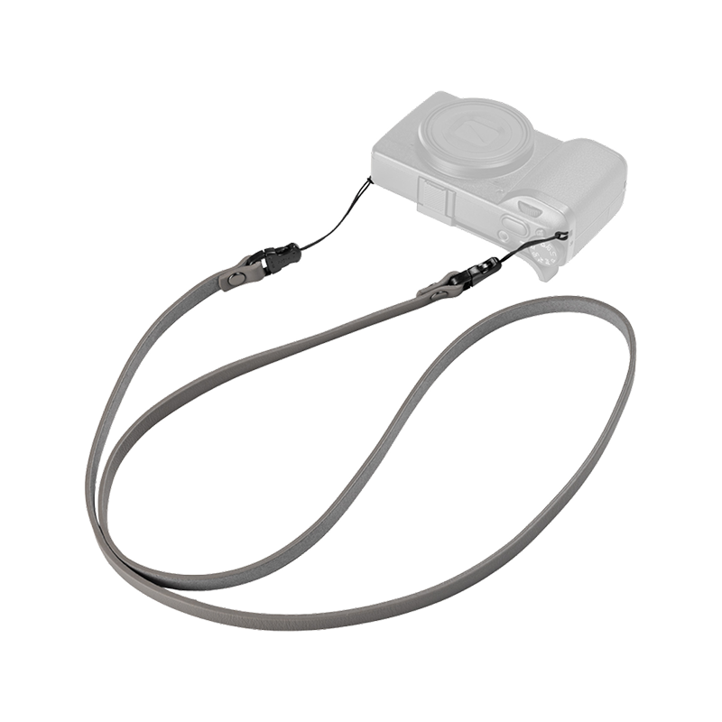 SmallRig quick release leather strap in gray, laid out with a compact camera