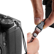 Hand pressing the quick-release buckle of a SmallRig strap on a camera