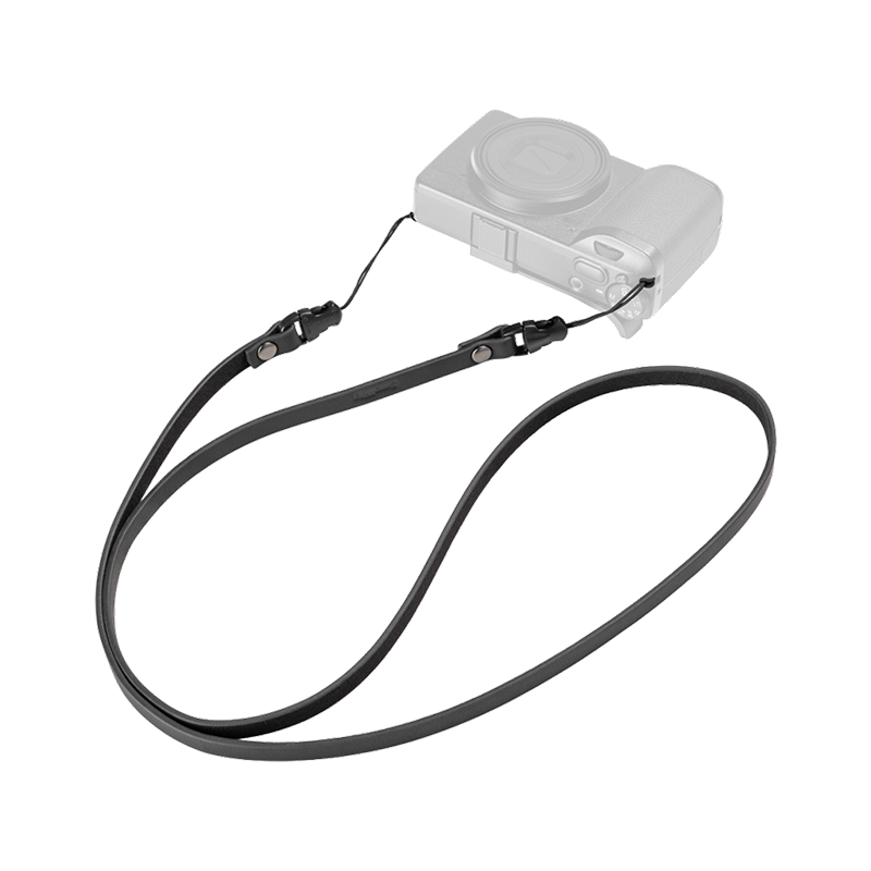 SmallRig quick release leather strap in black, laid out with a compact camera