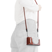 SmallRig quick release leather strap in red, worn over the shoulder with a camera in a case