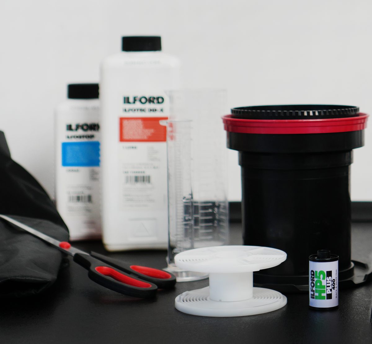 Un kit de revelado: revelador, baño de paro, probeta, tanque, espiral, tijeras y un carrete