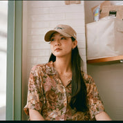 Woman wearing a floral shirt and beige cap indoors shot with Reflex Lab Pro 100 film 