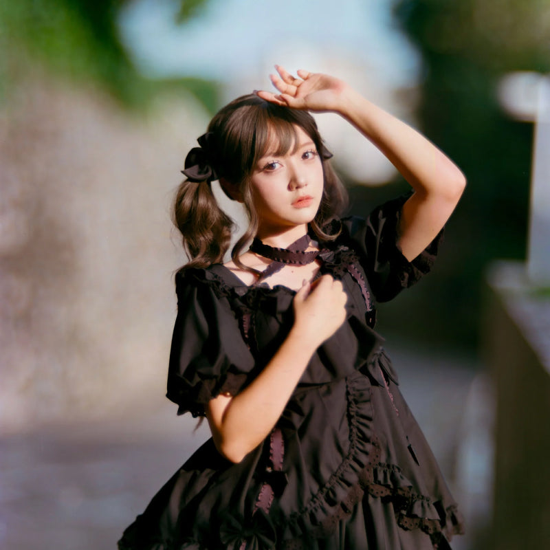 Woman in a black dress posing outdoors with a blurred background shot with Pro100 4x5 sheet film